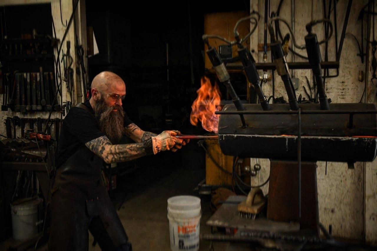 blacksmith putting metal in hot fire